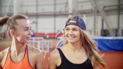 Two young athletic women friends running on a running track