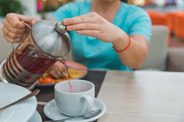 woman hands close up pouring fruit tea from kettle