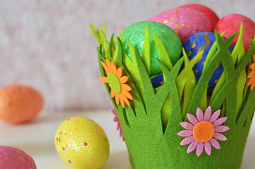 Happy Easter Day. Easter eggs concept. Closeup Colorful Easter eggs in nest and basket green crass on white wooden background.