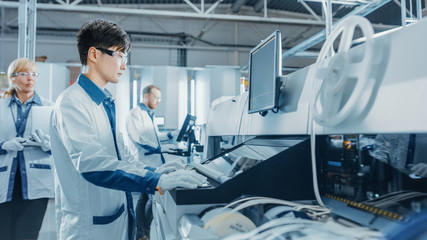 On High Tech Factory Asian Engineer Uses Computer for Programing Pick and Place Electronic...
