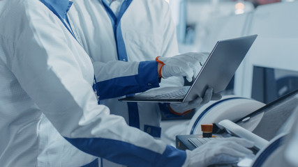 Close-up Shot of an Engineers Hands On High Tech Factory Using Computer for Programming Electronic...