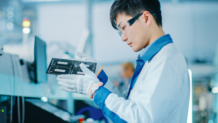 High-Tech Factory: Quality Control Engineer Checks Electronic Printed Circuit Board it for Damages....