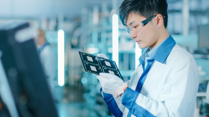 High-Tech Factory: Quality Control Inspector Checks Electronic Printed Circuit Board it for...