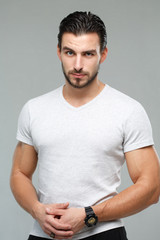 Attractive athletic man in a white shirt isolated on gray background.