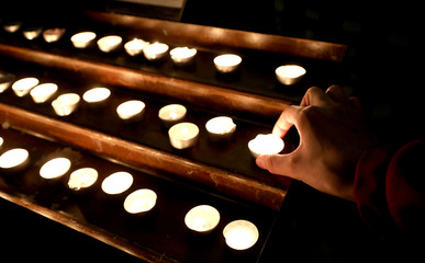 hand of the priest with many candles with the flame in the churc