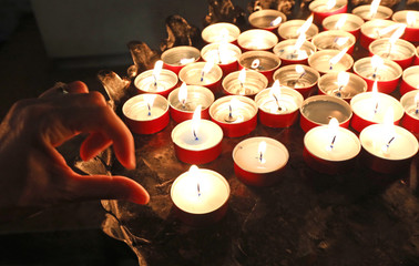 woman praying by lighting the candles in the place of worship