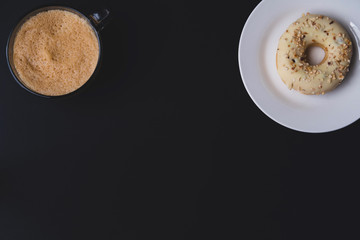 Flat lay with black background with coffee mug and donut 