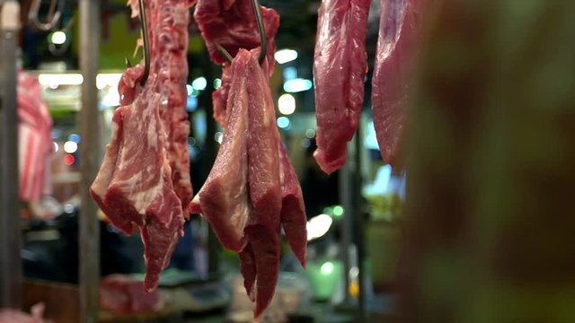 Slow motion of raw pig meat hanging on hook sale on market. Traditional taiwanese food selding in a shop located at market of Taipei. Popular famous marketplace of Taiwan -Dan
