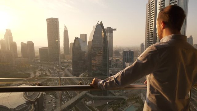 One Young Man Standing On Office Balcony Overlooking City Skyline