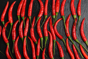 A lot of sharp hot spice red chilli cayenne pepper with wet drops of freshness water dew on a black graphite slate stone surface. Natural vegeterian diet organic vegetable background