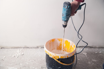 Man with a drill mixing paint. Renovation