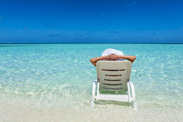Young woman resting in deck chair at the tropical beach 