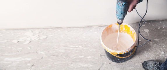 Man with a drill mixing paint. Renovation