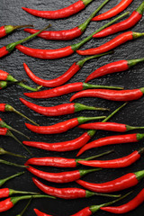 A lot of sharp hot spice red chilli cayenne pepper with wet drops of freshness water dew on a black graphite slate stone surface. Natural vegeterian diet organic vegetable. Dark food foto