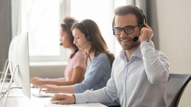 Smiling male call center operator in headset looking at camera