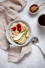 oatmeal with raspberries and pear in a rustic plate on a marble table. Morning concept with copy space