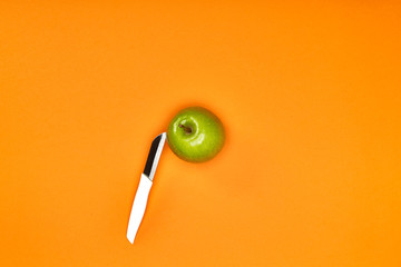Grüner Bio Apfel auf orangenem Hintergrund geschnitten