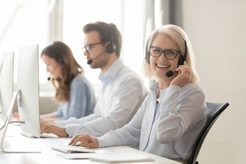 Happy mature female call center agent looking at camera smiling