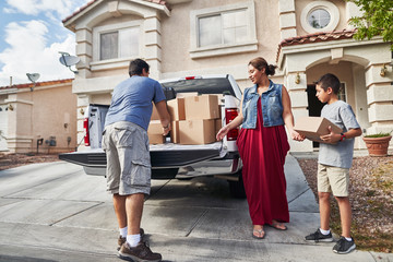 hispanic family unloading pickup truck and moving into new house in las vegas