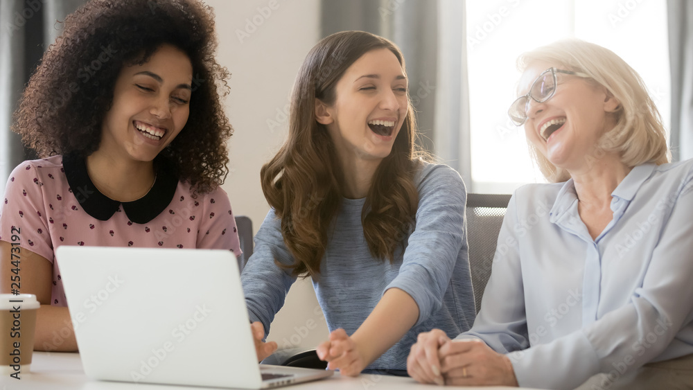 Wall mural cheerful african and caucasian businesswomen laughing having fun at workplace