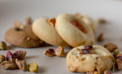 Pistachio butter cookies oven fresh with vanilla and chocolate base close up, with pistachios sprinkled in  on top of them isolated in a white background. 