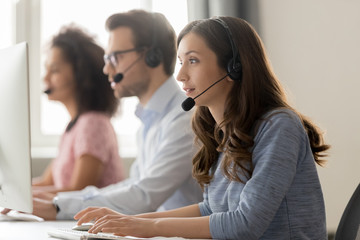 Young woman call center agent in headset consulting online client