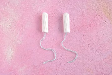 Two white cotton tampons with selective focus for monthly women&rsquo;s menstrual days. Clean hygiene absorbent tampon on pink textured plaster background. Protect care products for menstruation period day 