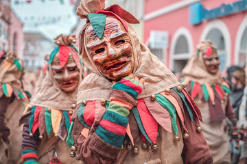 Friendly carnaval figure in brown, green, red robe shows hand gesture. Carnival in southern Germany - Black Forest