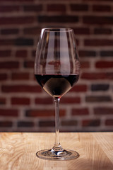 Red semi-sweet grape naturally tasty wine in an elegant glass goblet stands on a wooden table in a restaurant. A great addition to dinner