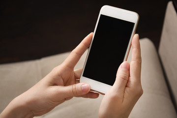 Female hands hold white phone in their hands. Mobile phone close-up.