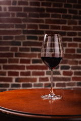 Red semi-sweet grape naturally tasty wine in an elegant glass goblet stands on a wooden table in a restaurant. A great addition to dinner