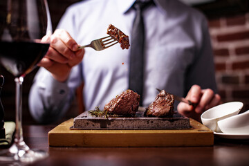 sirloin steak on a very hot stone being cooked by a man to his own taste on a wooden table with a...