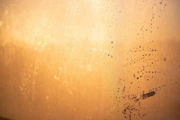 Abstract texture, orange, metallic, spots on the misted glass.