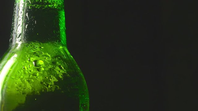 cold beer in a green bottle with water drops on a dark background. 4K UHD video 3840x2160