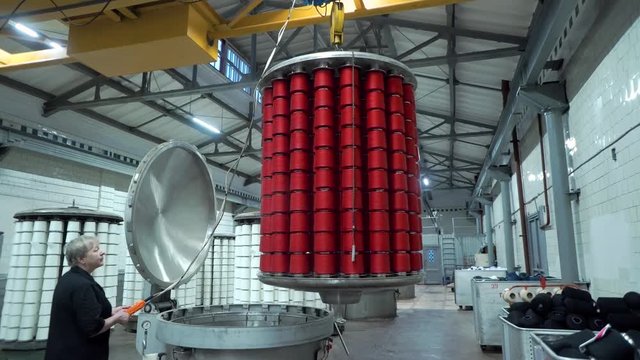 Textile factory female worker works with thread coloring machine. Modern technology in dyeing yarns with Machines for Textile Industry, Dyeing Machine Chemical Tanks