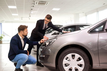 Plakat Customer and salesman choose a car in the showroom