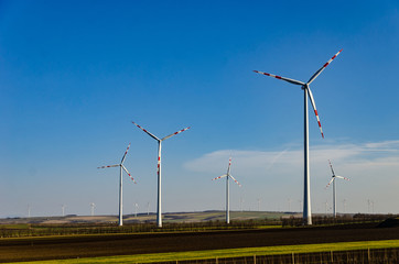 Windmill in a green field against a blue sky. Naturally friendly resource extraction systems.