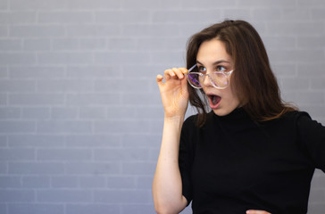 Young woman with glasses in her hands covered her mouth