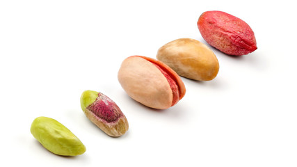 Pistachios in different stages from peeled green fruit, through roasted and salted to raw in purple skin, isolated on white background.