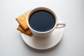 Cup of black coffee with crackers on saucer on white background