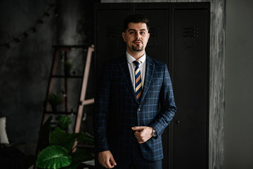 A handsome man in a blue suit in a cage posing in the Studio. Business portrait.