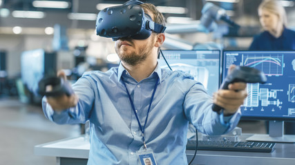 Portrait Shot of the Industrial Engineer Wearing Virtual Reality Headset and Using Controllers,...