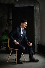 A handsome man in a blue suit in a cage posing in the Studio. Business portrait.