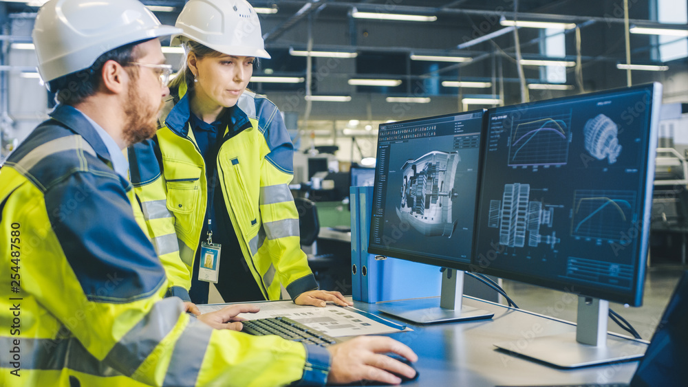 Poster at the factory: male mechanical engineer and female chief engineer work together on the personal com