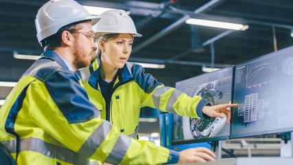 Inside Factory Male Mechanical Engineer and Female Chief Engineer Work Together on the Personal Computer, They Discuss Details of the 3D Engine Model Design.