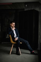 A handsome man in a blue suit in a cage posing in the Studio. Business portrait.