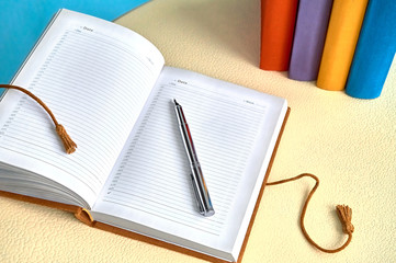 Open vintage leather dated notebook pen and books on white table Workplace                               