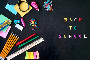 Fototapeta na wymiar Back to school concept, education equipment, colored school office supplies on blackboard background. Top view.