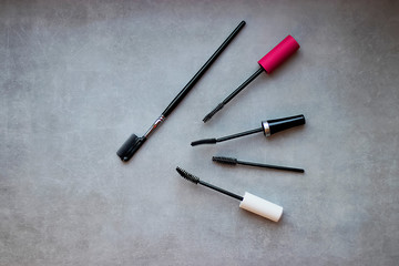Brushes for mascara and comb for eyelashes on a gray background.