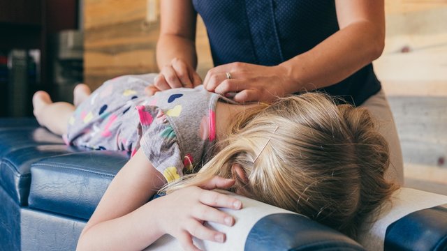Young Girl Being Adjusted by Chiropractor